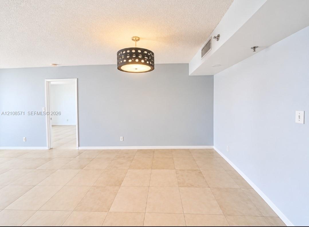 Neutral-toned tile flooring, light-colored walls, and a decorative drum-style ceiling light fixture