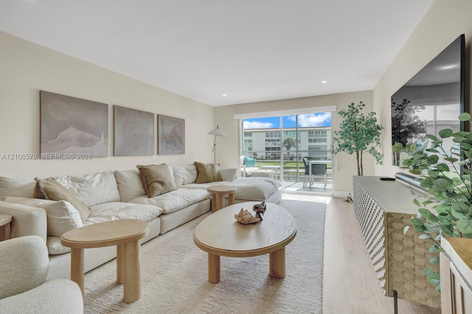 Living area featuring wood-finish flooring, recessed lighting, and a large sliding glass door opening to a screened-in lanai
