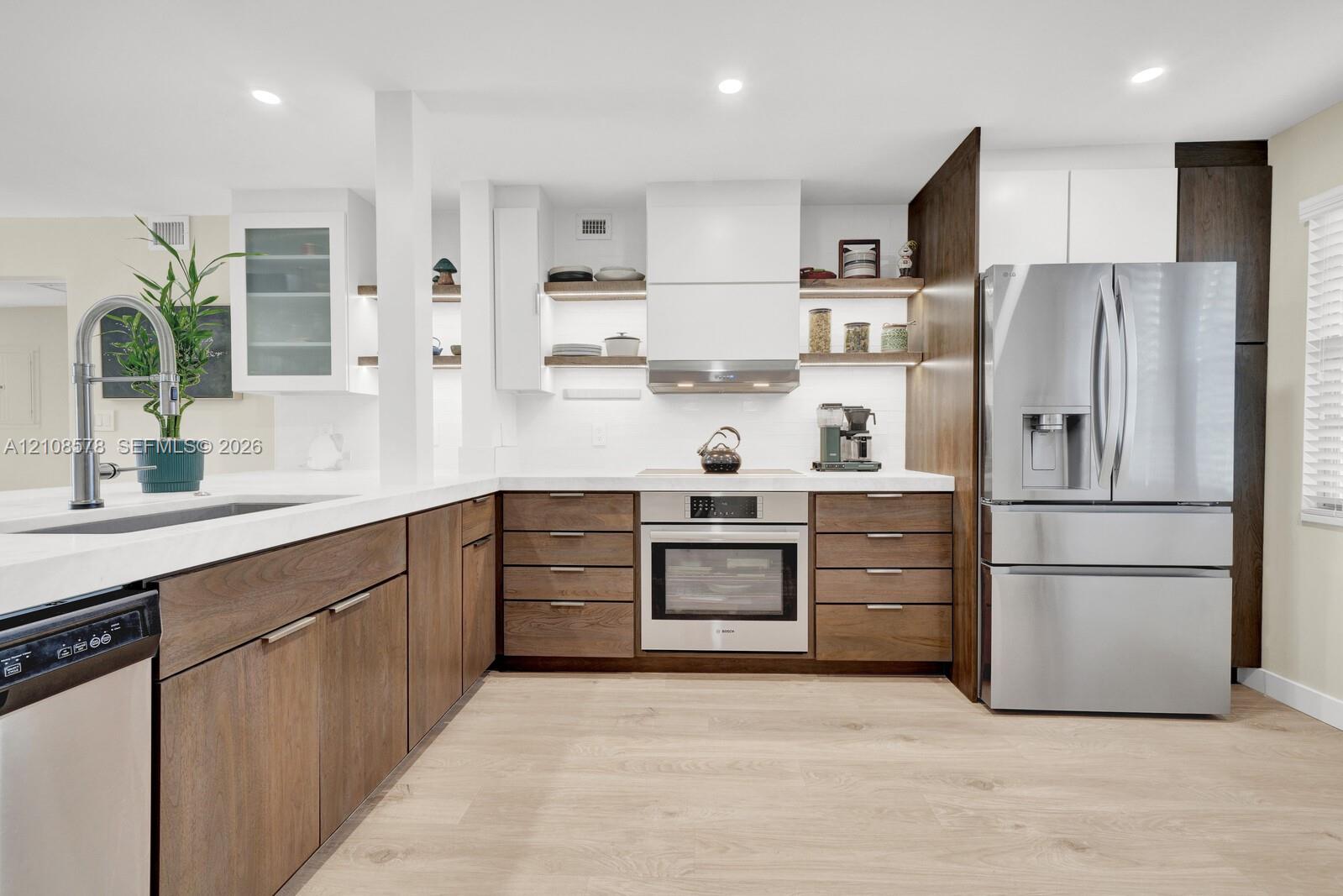 Kitchen featuring wood-finish cabinetry, white countertops, recessed lighting, stainless steel appliances, and integrated open shelving
