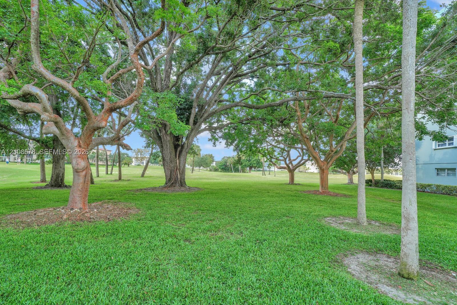 Expansive grounds featuring mature shade trees, established landscaping, and open green space