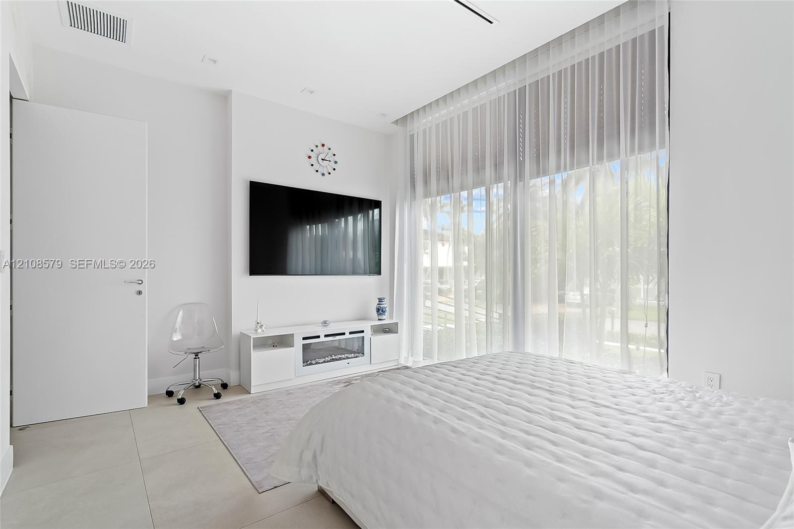 Floor-to-ceiling windows with floor-length treatments, large-format tile flooring, flush-mount ceiling lighting, and a crisp white interior finish
