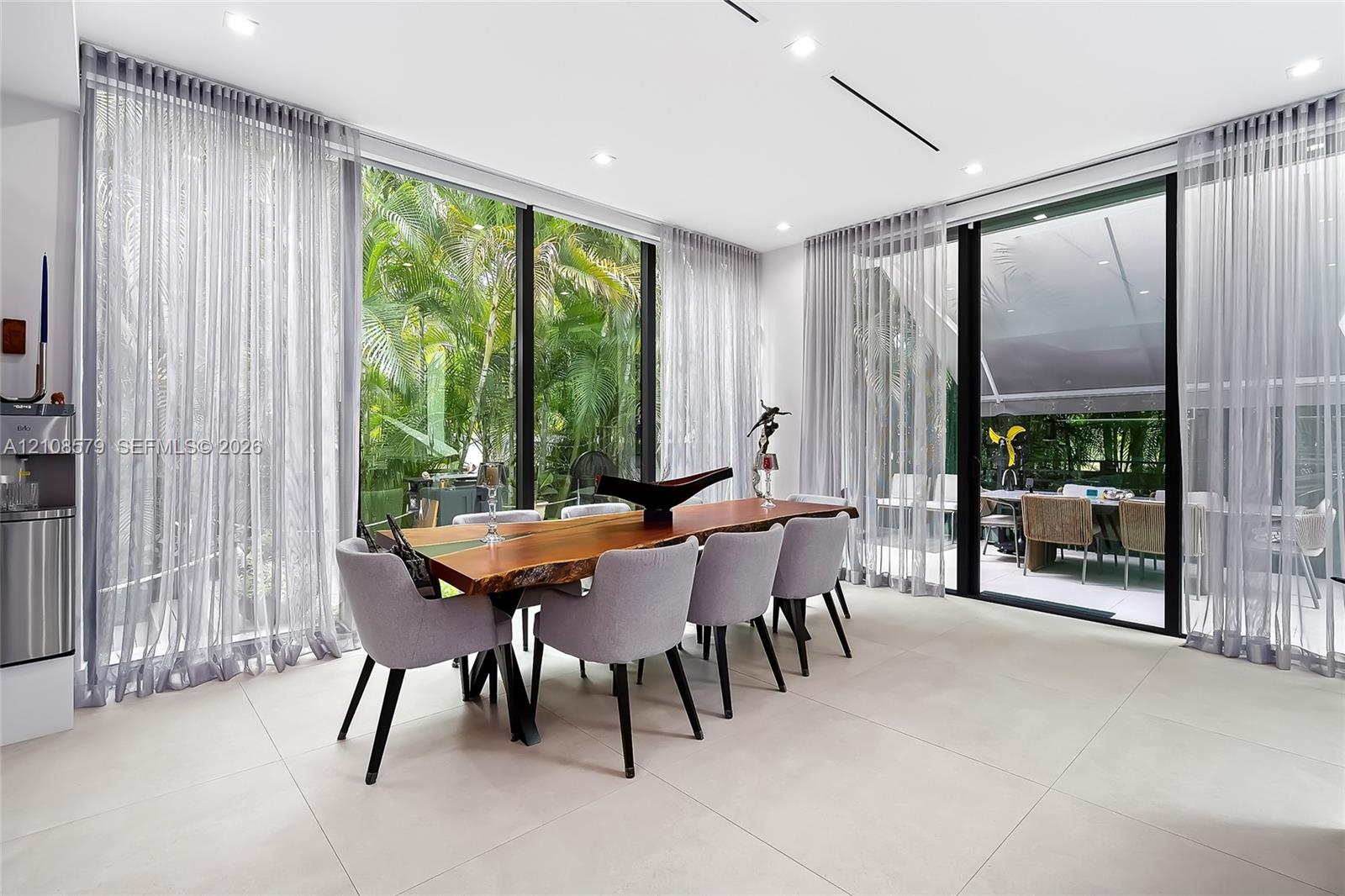 Floor-to-ceiling glass walls, large-format tile flooring, recessed ceiling lighting, and sliding glass panel doors