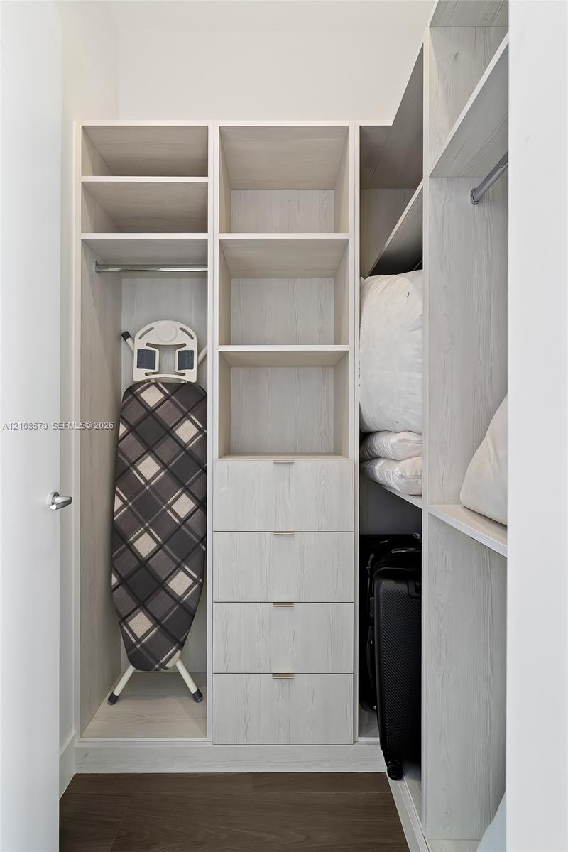 Custom built-in closet featuring light wood-finish shelving, integrated drawers with metal pulls, and multiple clothing rods