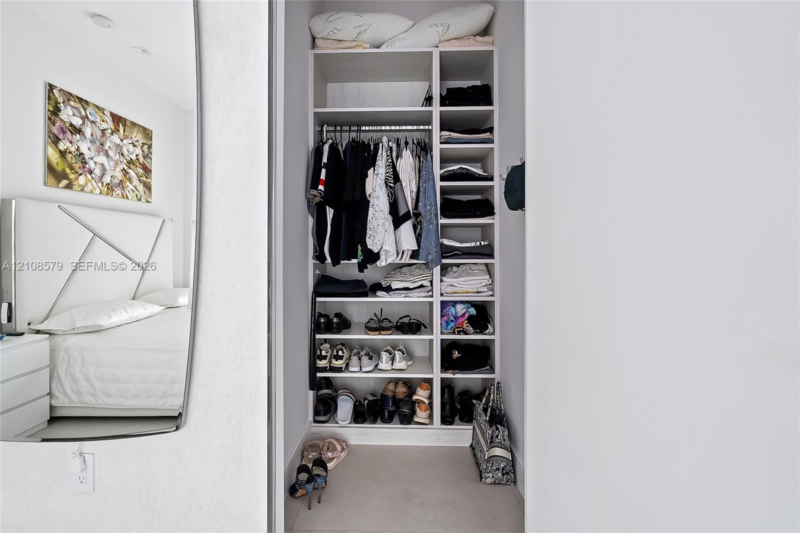 Built-in closet featuring multi-level shelving, integrated hanging rods, and a white finish