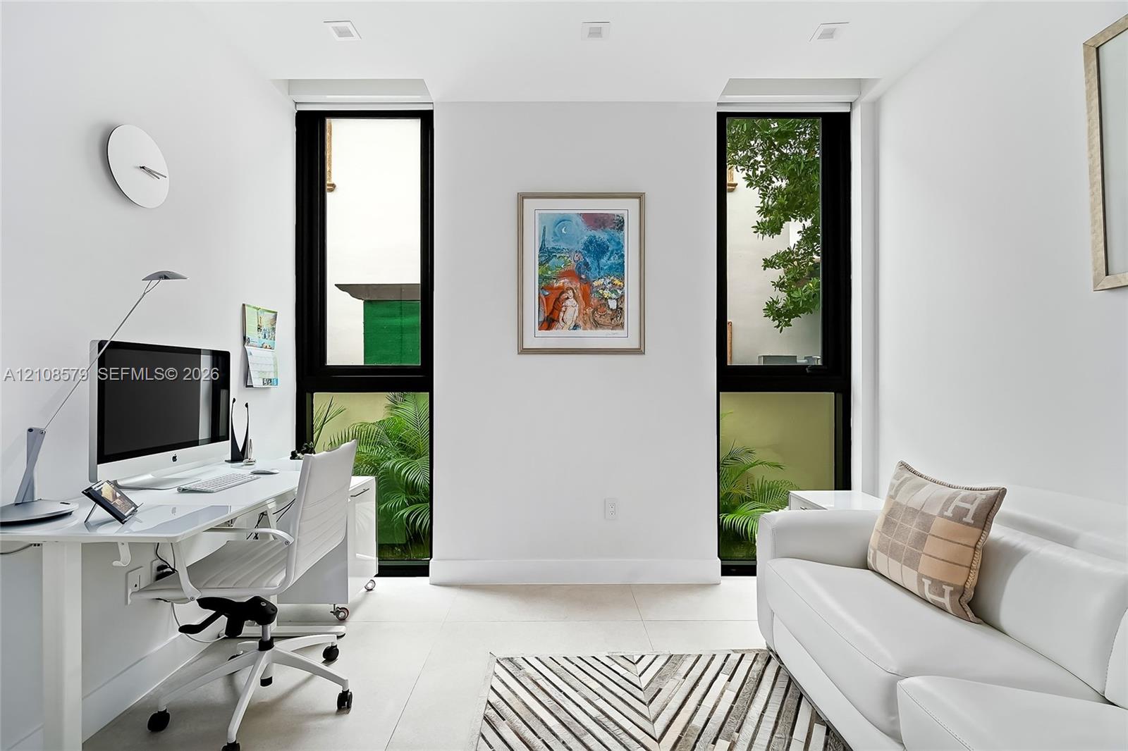 Bright room featuring large, floor-to-ceiling windows with black frames, recessed ceiling lighting, and light-toned tile flooring