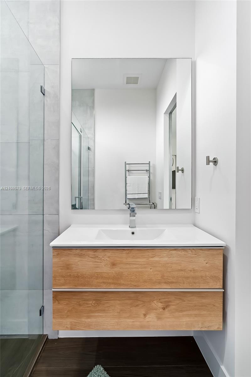 Floating wood-finish vanity with two drawers, integrated rectangular sink, wall-mounted faucet, and large frameless mirror