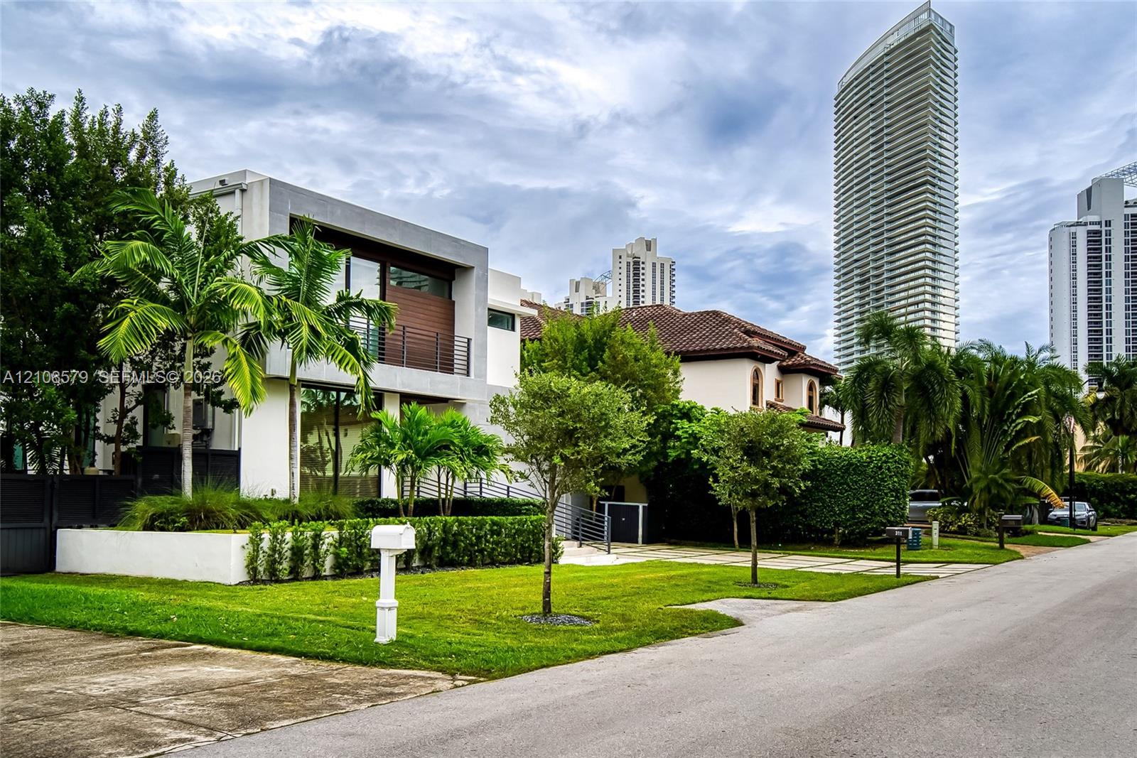 Contemporary exterior featuring clean concrete lines, a second-level balcony with horizontal slat screening, floor-to-ceiling windows, and integrated landscaping