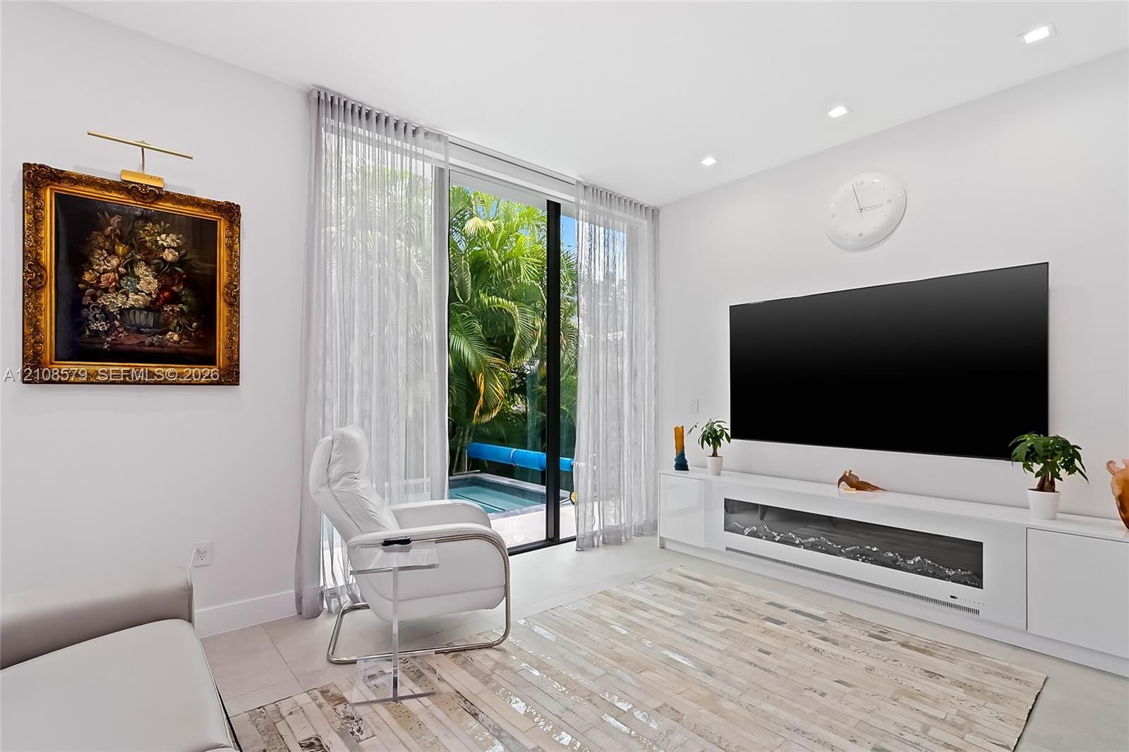 Living area featuring floor-to-ceiling glass sliding doors, built-in media cabinetry with integrated electric fireplace, and recessed lighting