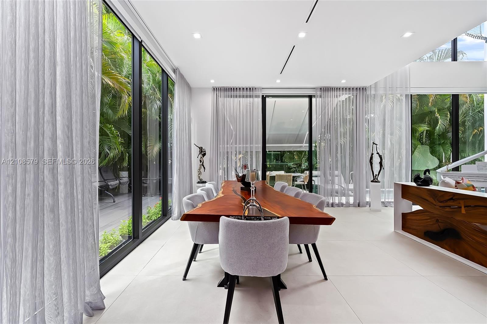 Floor-to-ceiling black-framed windows, large-format tile flooring, recessed linear lighting, and architectural built-in cabinetry