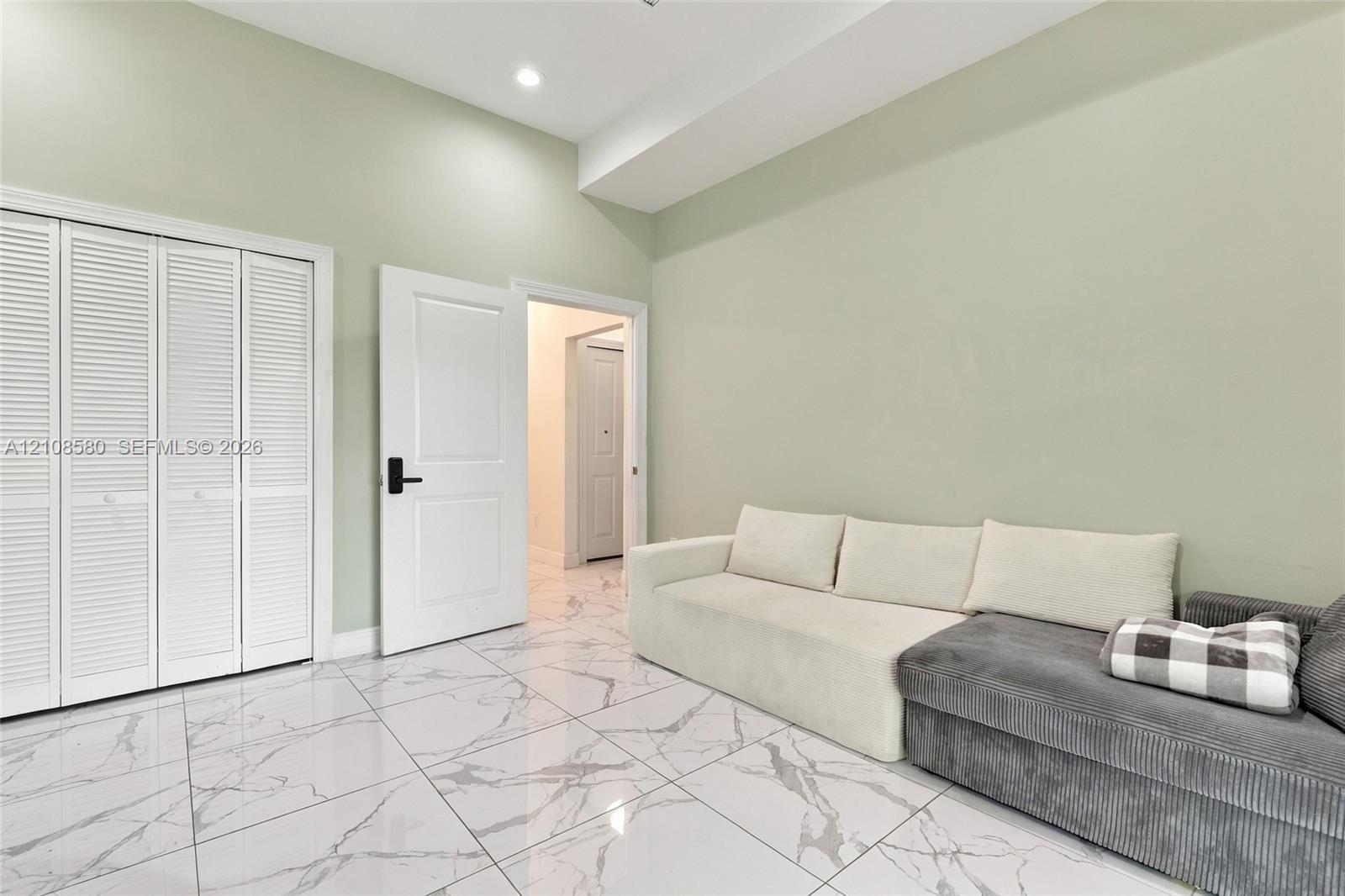 Interior space featuring white stone-finish tile flooring, louvered closet doors, and a recessed ceiling light
