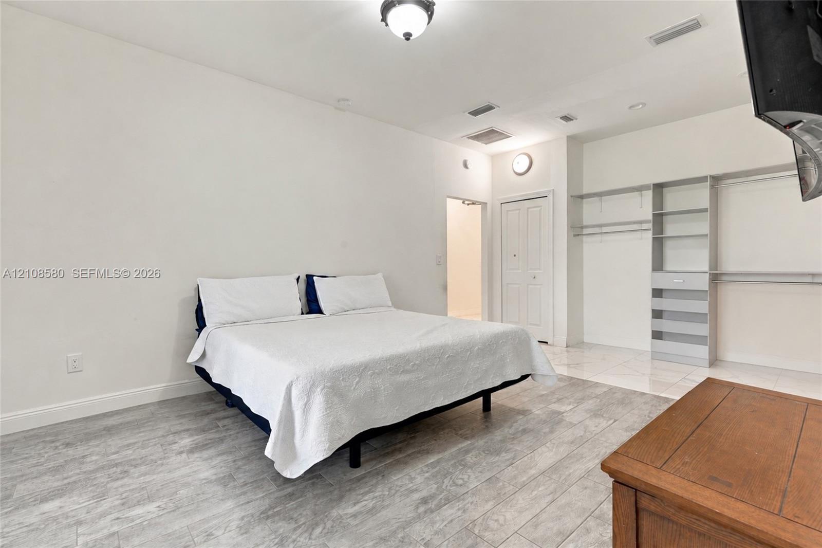 Room featuring wood-finish tile flooring, recessed lighting, and built-in gray shelving with integrated hanging rods