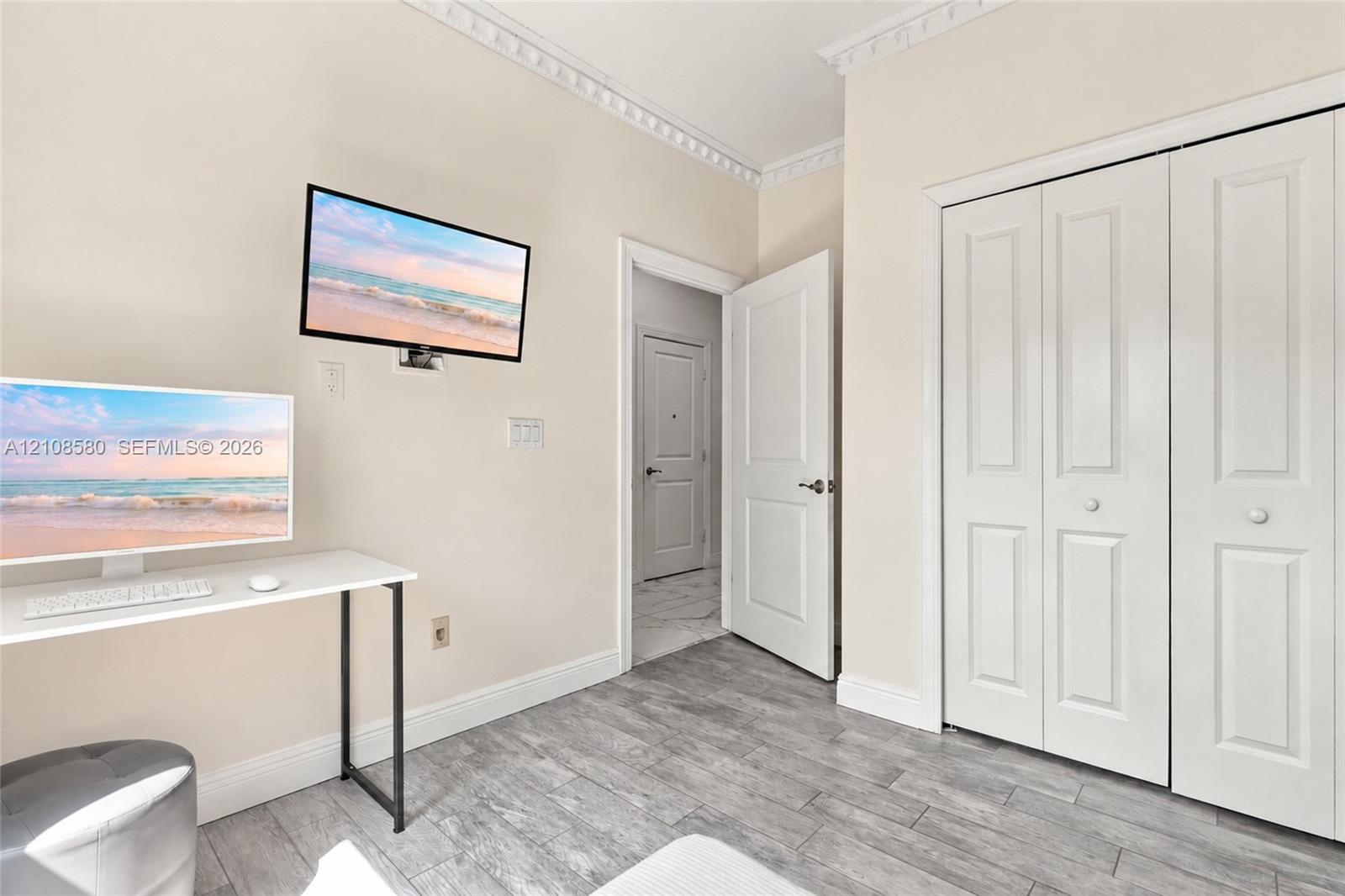 Wood-finish plank flooring, decorative crown molding, two-panel interior doors, and double-panel bifold closet doors