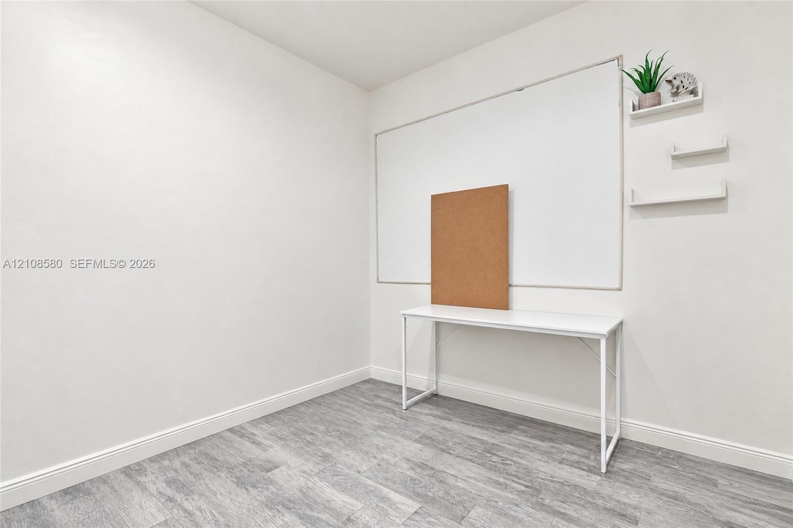Neutral interior space featuring wood-finish flooring and three wall-mounted floating shelves
