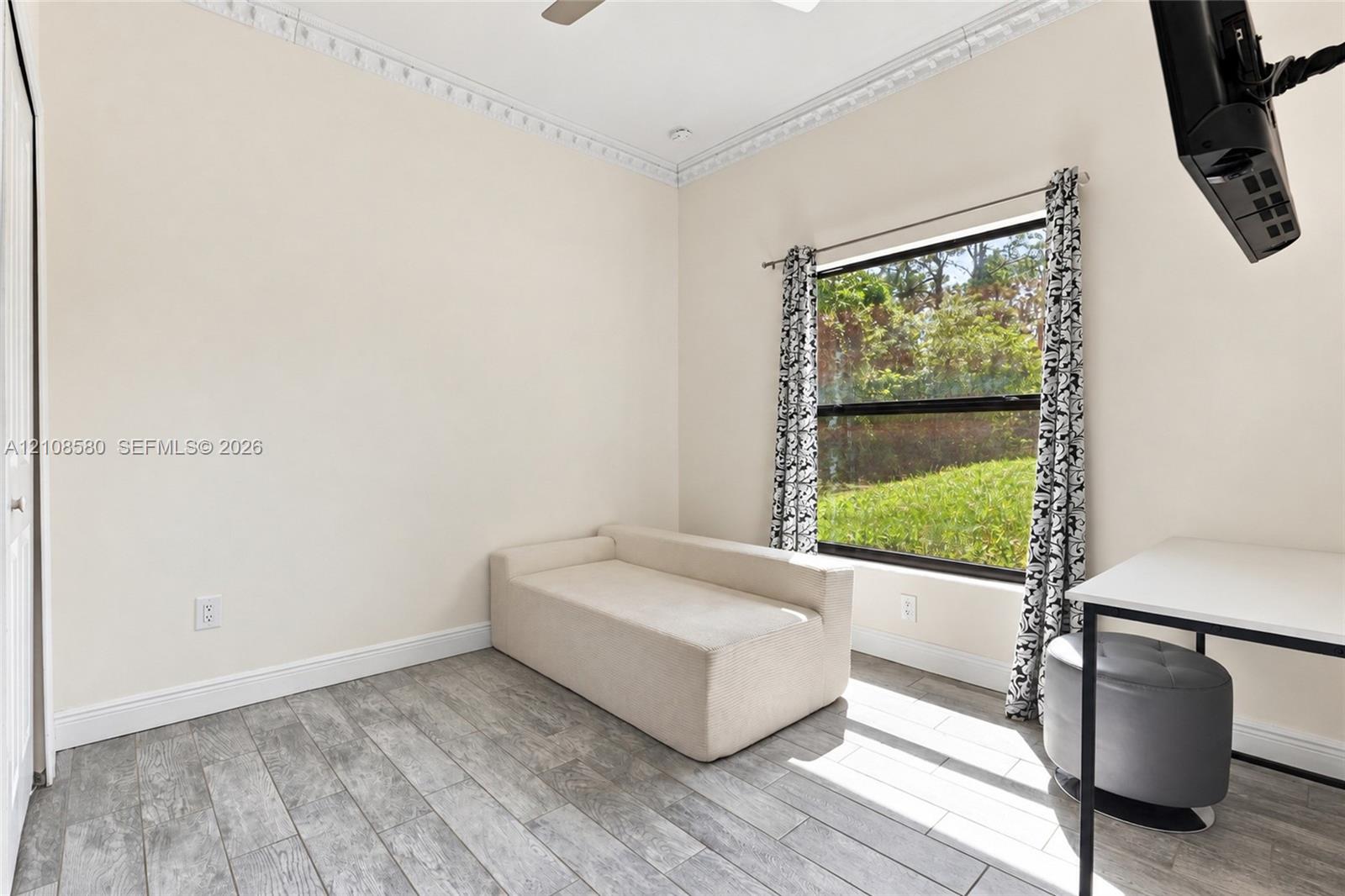 Room featuring wood-finish tile flooring, decorative crown molding, and a large window