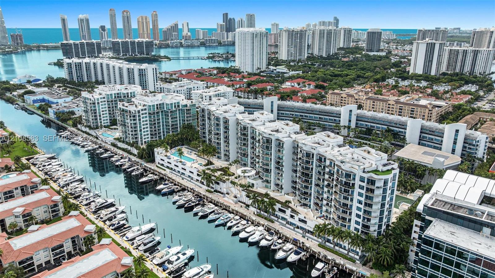 Aerial perspective featuring waterfront residential buildings, deep-water canal boat slips, and an expansive cityscape backdrop Aerial perspective featuring waterfront residential buildings, deep-water canal boat slips, and an expansive cityscape backdrop