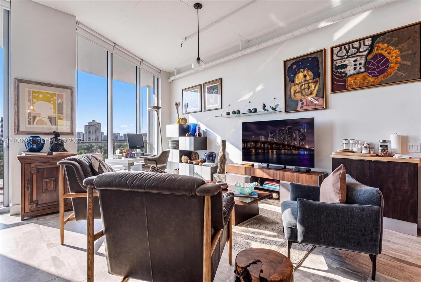 Living area featuring floor-to-ceiling windows, high ceilings, exposed ductwork, wood-finish flooring, and a built-in dark wood-finish cabinet Living area featuring floor-to-ceiling windows, high ceilings, exposed ductwork, wood-finish flooring, and a built-in dark wood-finish cabinet