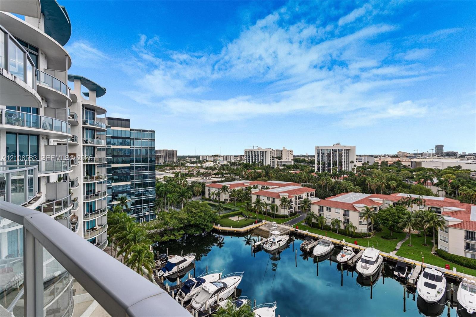 Curved balcony with glass railing overlooking a private marina with deep-water boat slips and manicured grounds