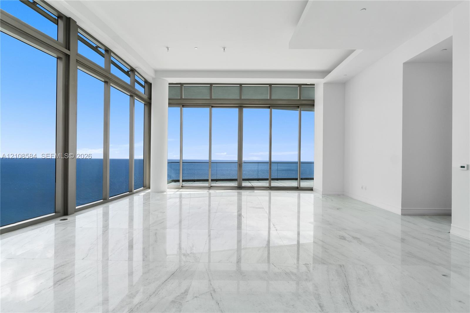 Floor-to-ceiling windows, polished stone flooring, recessed ceiling detailing, and glass-railing balcony