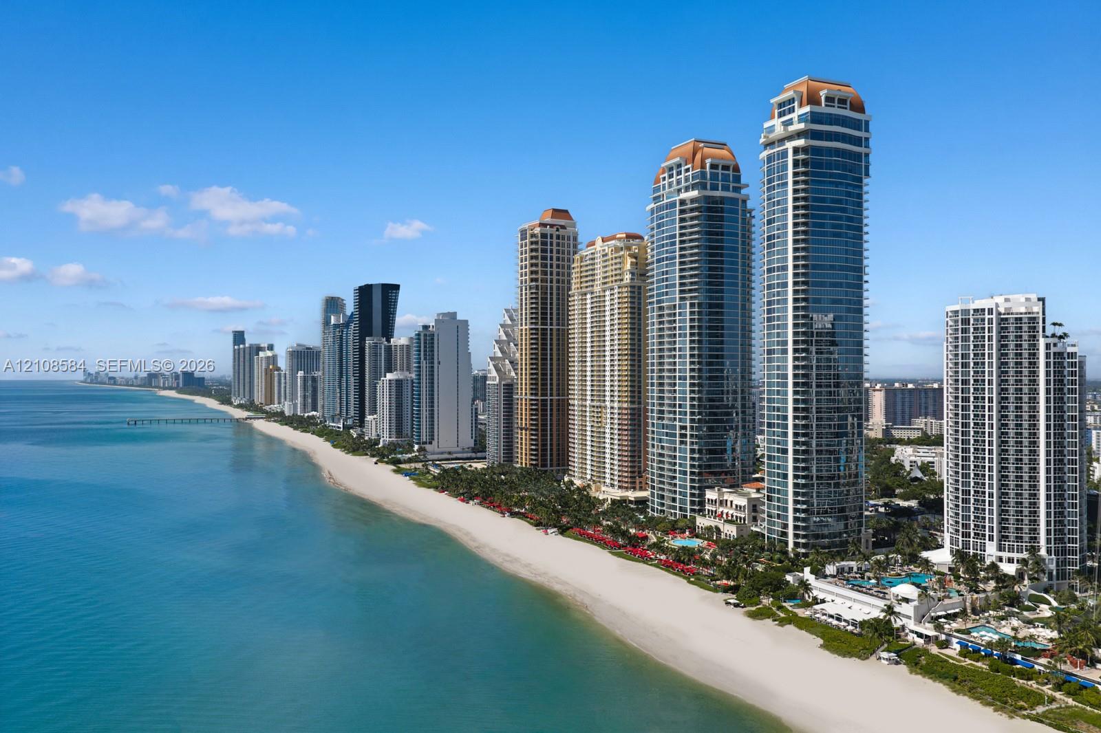 High-rise coastal towers featuring extensive glass curtain walls, expansive sandy shoreline, and direct maritime proximity