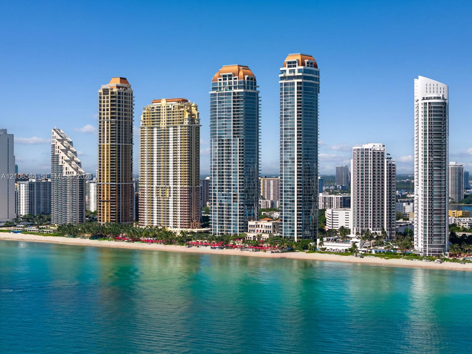Aerial perspective of beachfront high-rise residential towers featuring glass-facade architecture, direct sand access, and extensive ocean frontage Aerial perspective of beachfront high-rise residential towers featuring glass-facade architecture, direct sand access, and extensive ocean frontage
