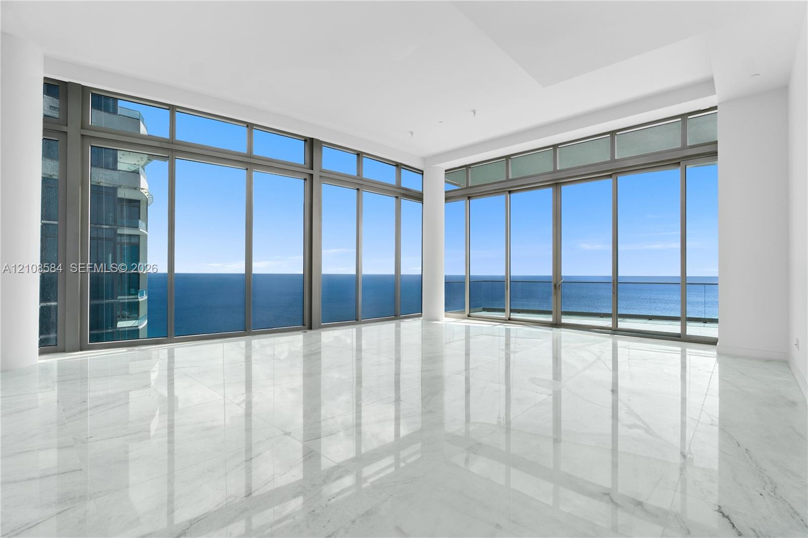 Floor-to-ceiling windows, polished stone flooring, recessed ceiling lighting, and a glass-paneled balcony