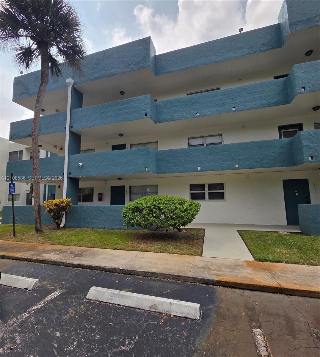 Multi-story building exterior featuring a textured stucco facade with recessed balconies and integrated surface lighting