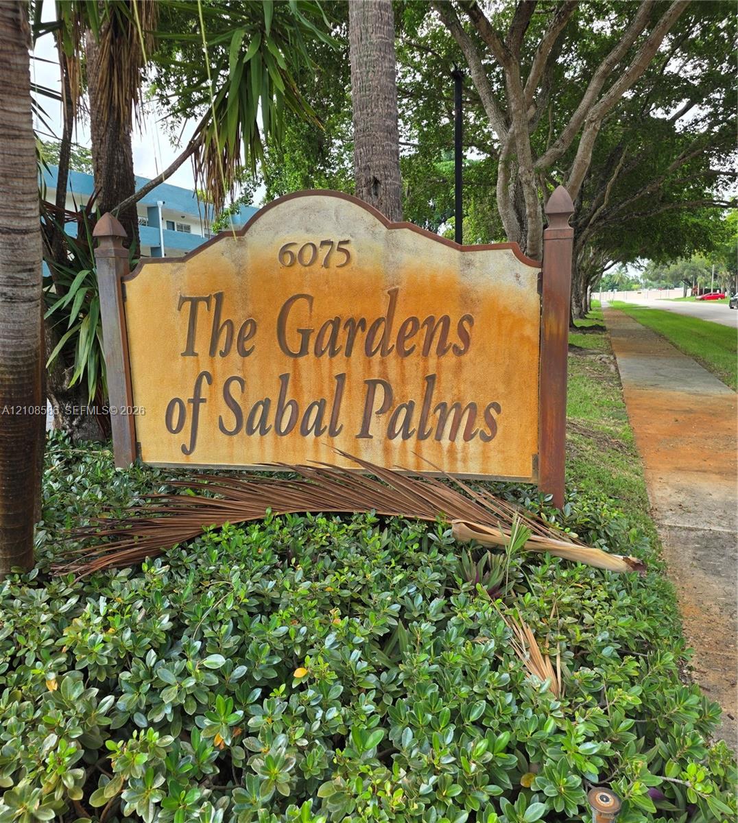 Custom monument sign featuring decorative wooden posts and mature landscape hedging