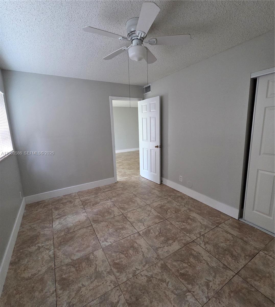 Neutral-toned interior featuring ceramic tile flooring, a central ceiling fan with integrated light fixture, and six-panel interior doors