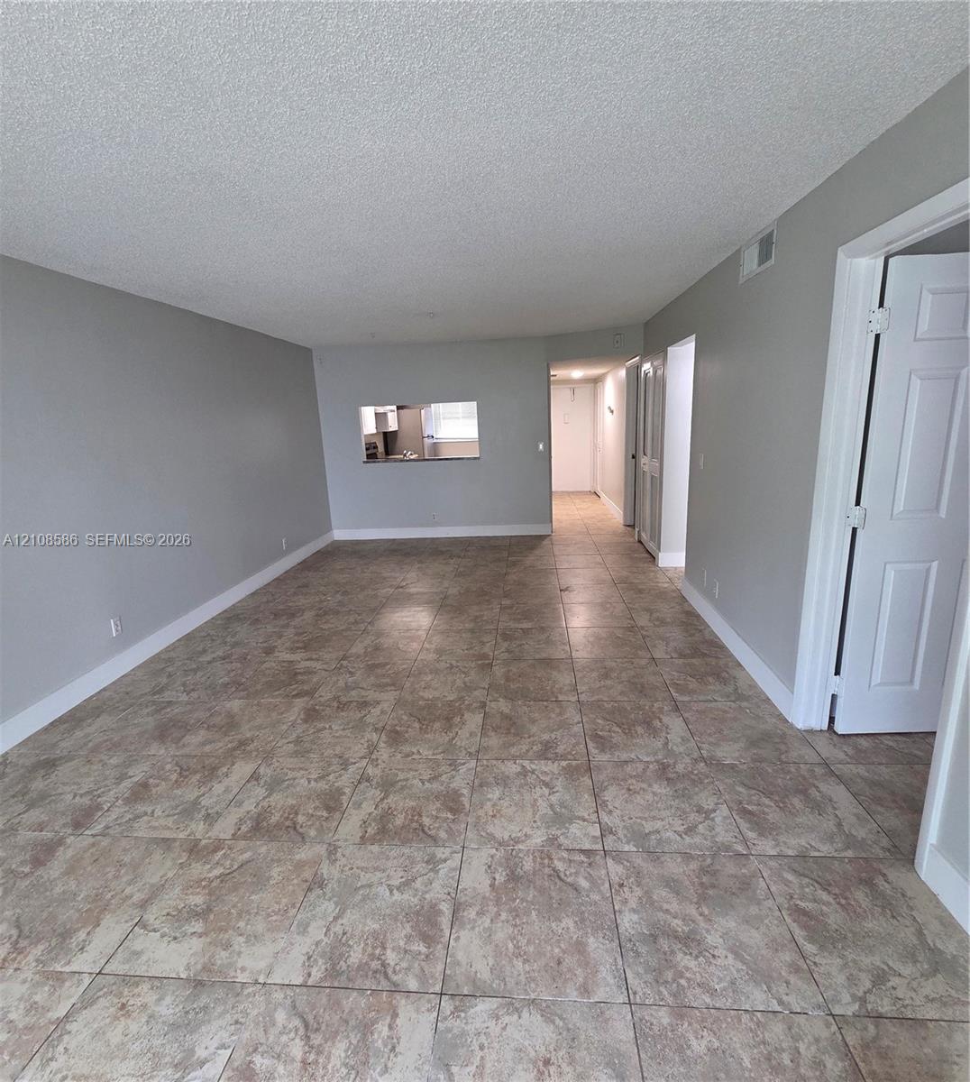 Neutral-toned interior featuring large-format ceramic floor tile, pass-through opening, and six-panel interior doors