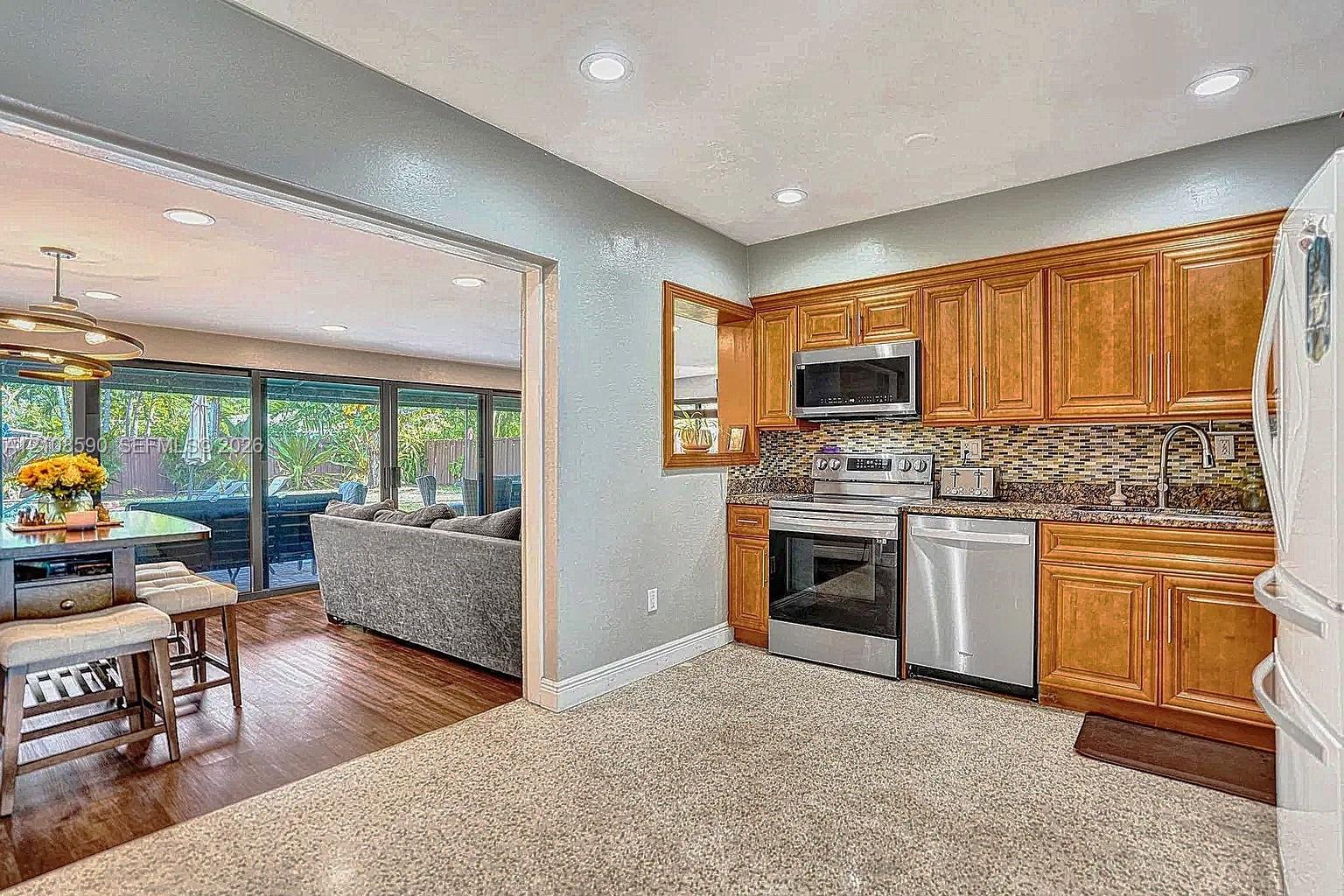 Kitchen featuring wood cabinetry, stainless steel appliances, multi-tonal decorative backsplash, and recessed lighting
