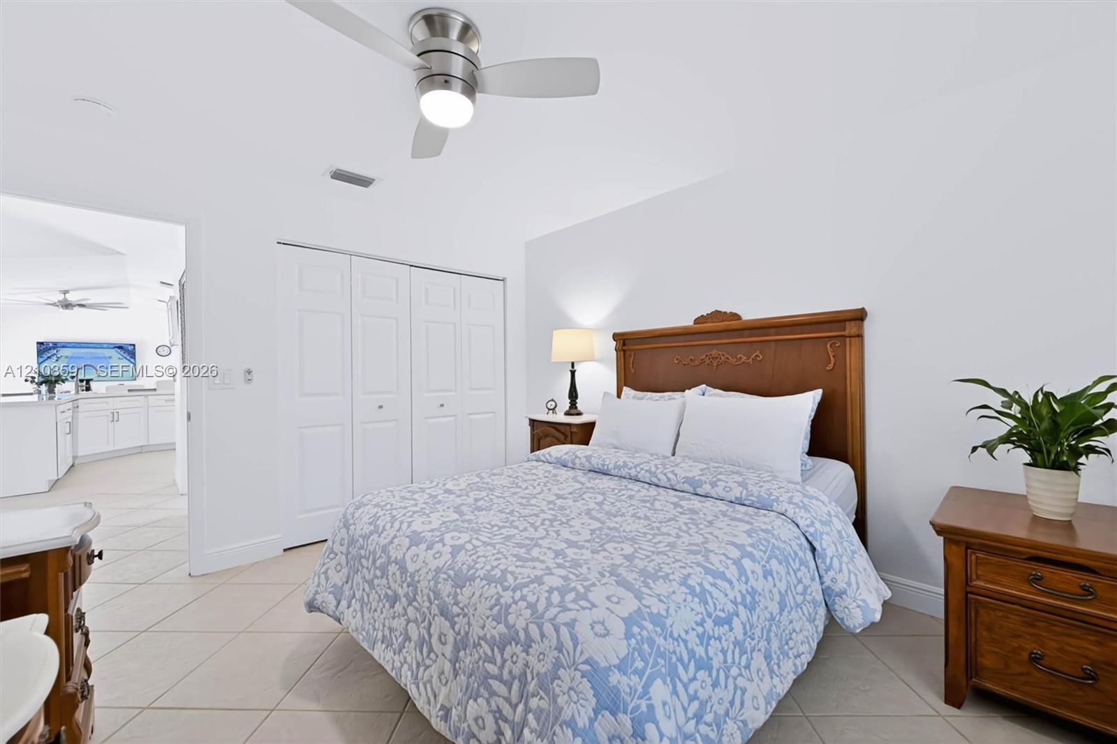 Neutral wall finishes, ceramic tile flooring, brushed-nickel ceiling fan with integrated lighting, and multi-panel closet doors