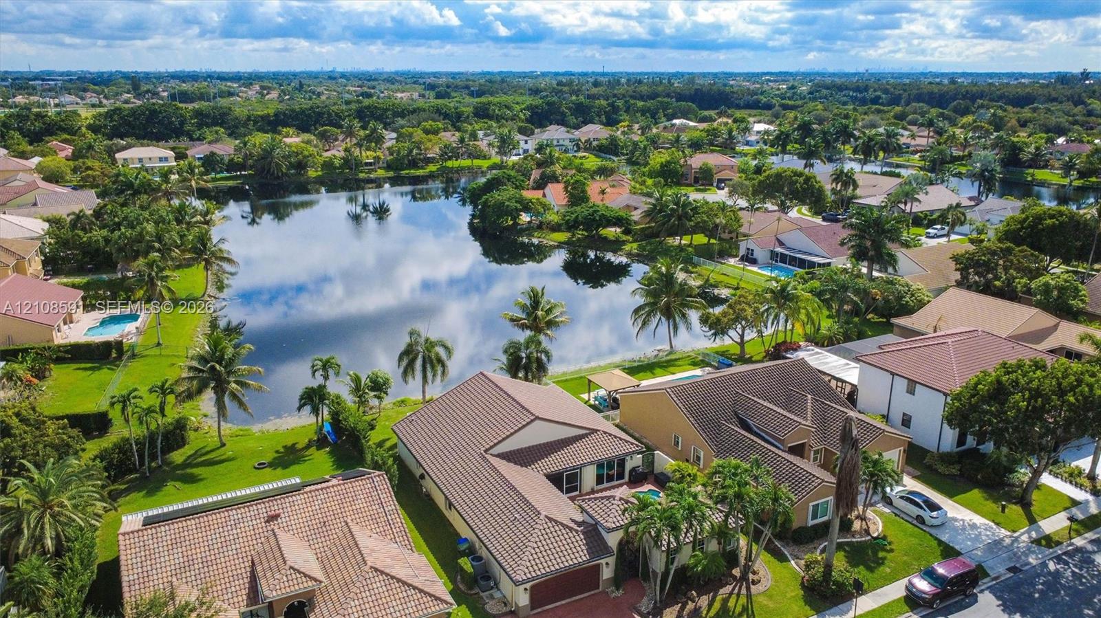 Aerial perspective featuring a waterfront setting, tiled rooflines, manicured lawns, and mature landscaping
