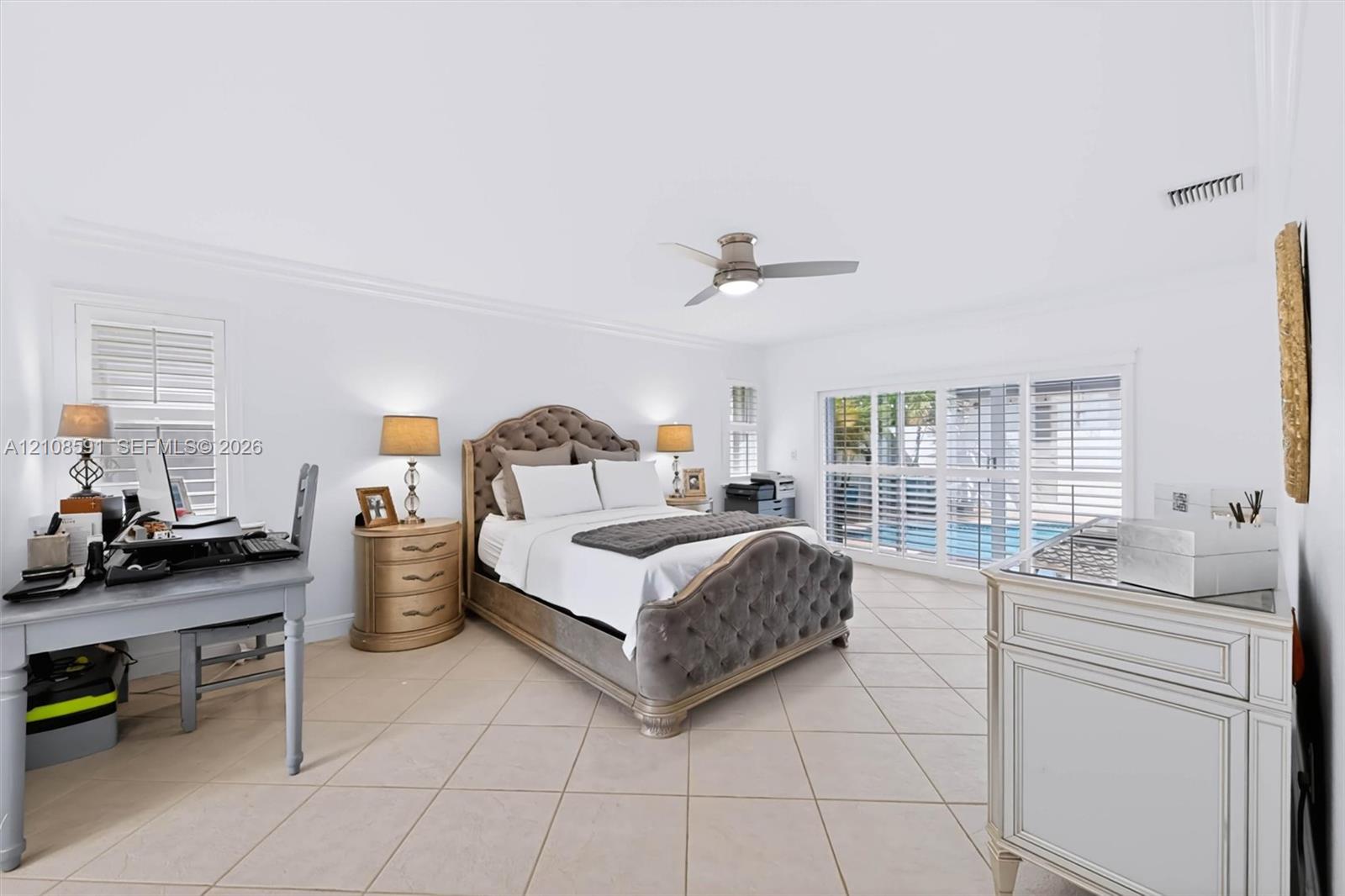 Neutral tile flooring, ceiling fan with integrated lighting, and plantation shutters covering large sliding glass doors