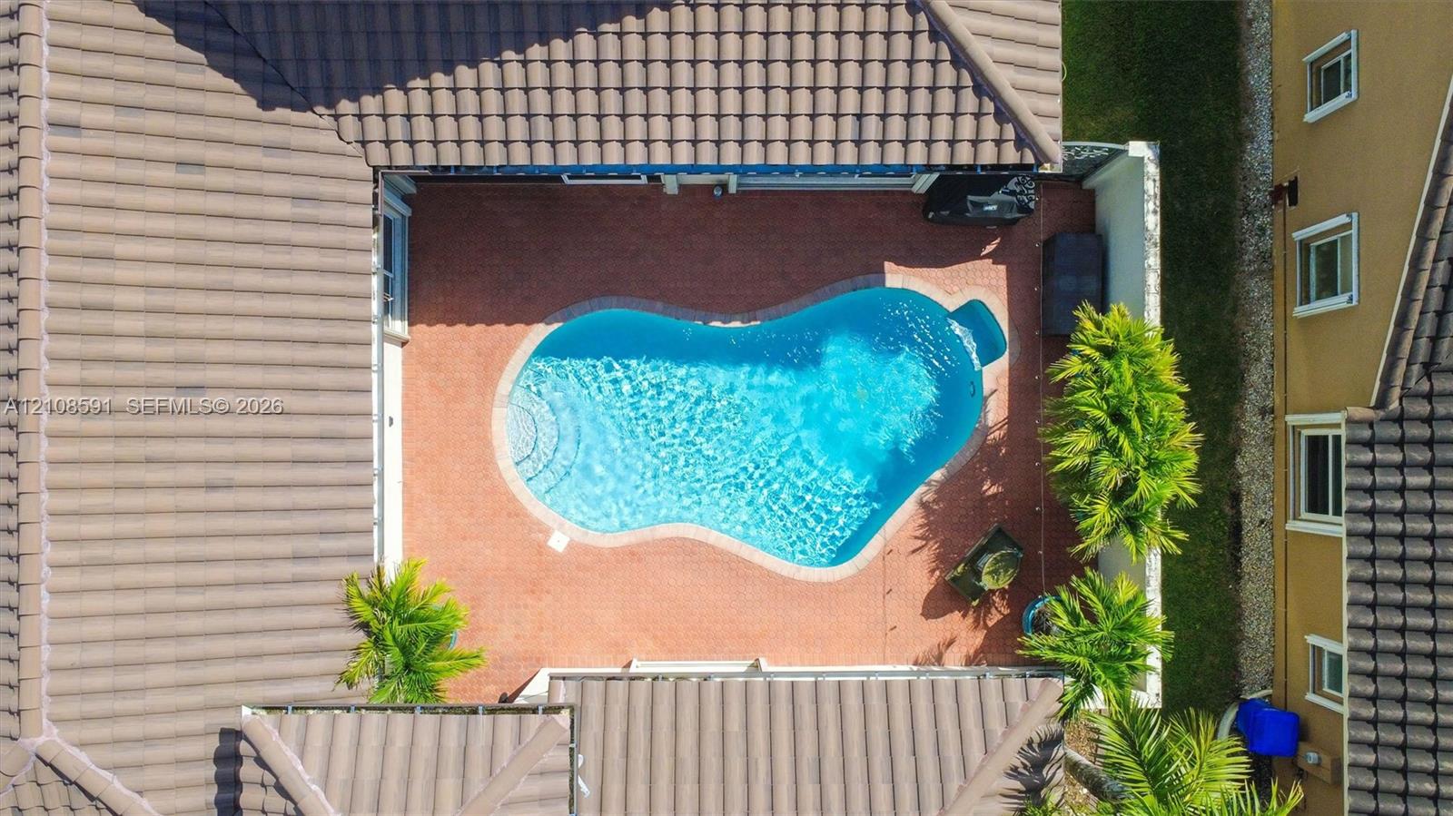 Courtyard featuring a free-form swimming pool, paved patio, and tiled roof structure