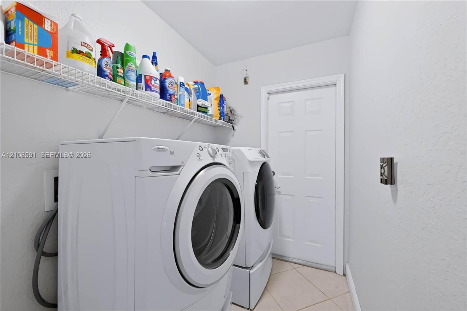 Utility area featuring ceramic tile flooring, a six-panel door, and white wire wall-mounted shelving
