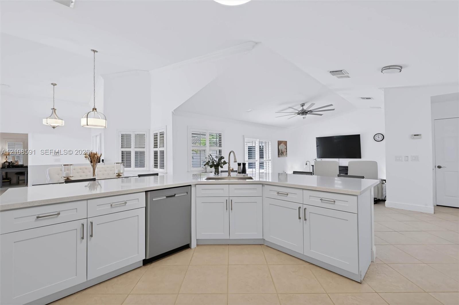Kitchen featuring a central island with a stone-surface countertop, stainless steel dishwasher, undermount sink, shaker-style cabinetry, and pendant lighting
