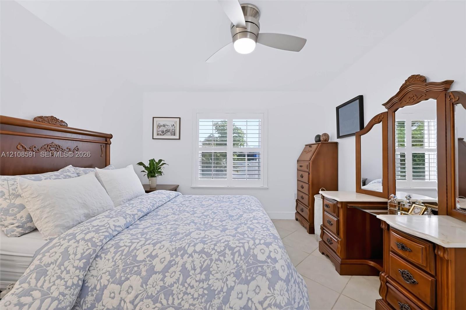 Neutral-toned tile flooring, white plantation shutters, and a brushed-nickel ceiling fan with integrated lighting