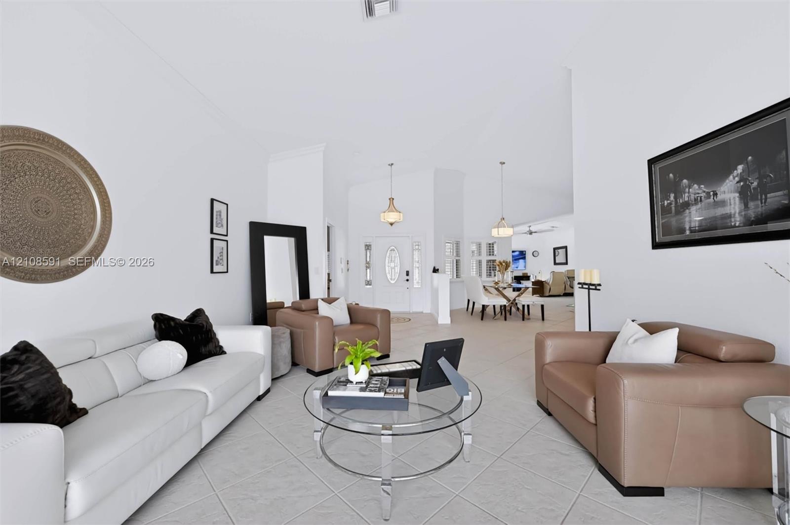Vaulted ceilings, large-format tile flooring, dual hanging pendant light fixtures, and glass-paneled entry door