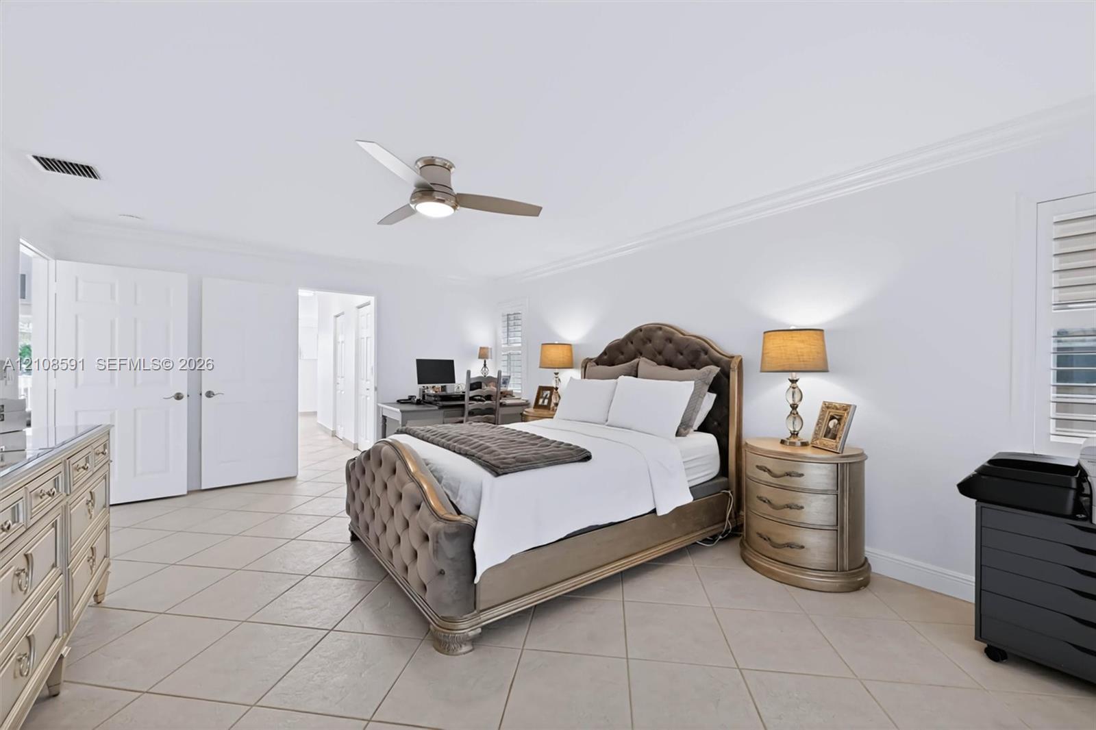 Neutral tile flooring, crown molding, multi-panel doors, and a ceiling fan with integrated lighting