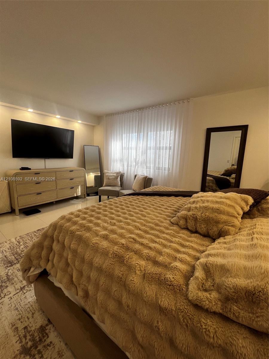 Neutral-toned room featuring light-colored tile flooring, recessed ceiling lighting, and floor-to-ceiling sheer window treatments