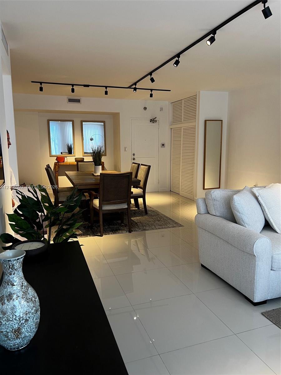Large-format tile flooring, adjustable overhead track lighting, and louvered-panel built-in closet doors