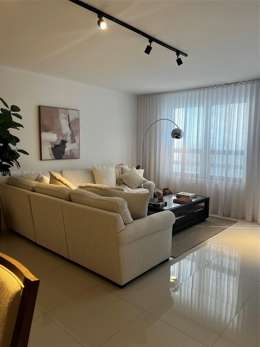 Polished tile flooring, black track lighting, and floor-to-ceiling sheer window treatments