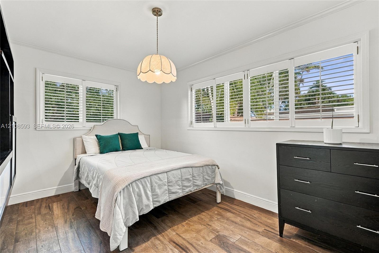 Wood-finish flooring, multi-pane windows with integrated shutters, and a scalloped glass pendant light fixture