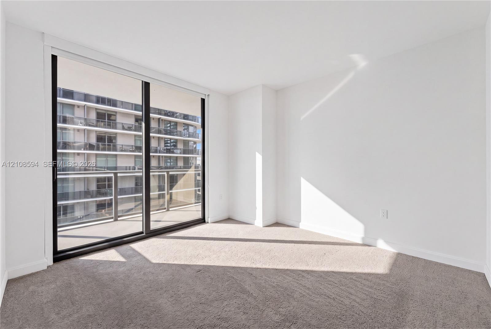 Full-height sliding glass door, neutral carpeting, and private balcony access
