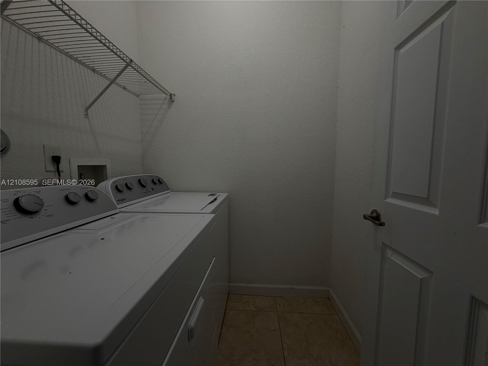 Laundry area featuring tile flooring, a six-panel door, and integrated wall-mounted wire shelving
