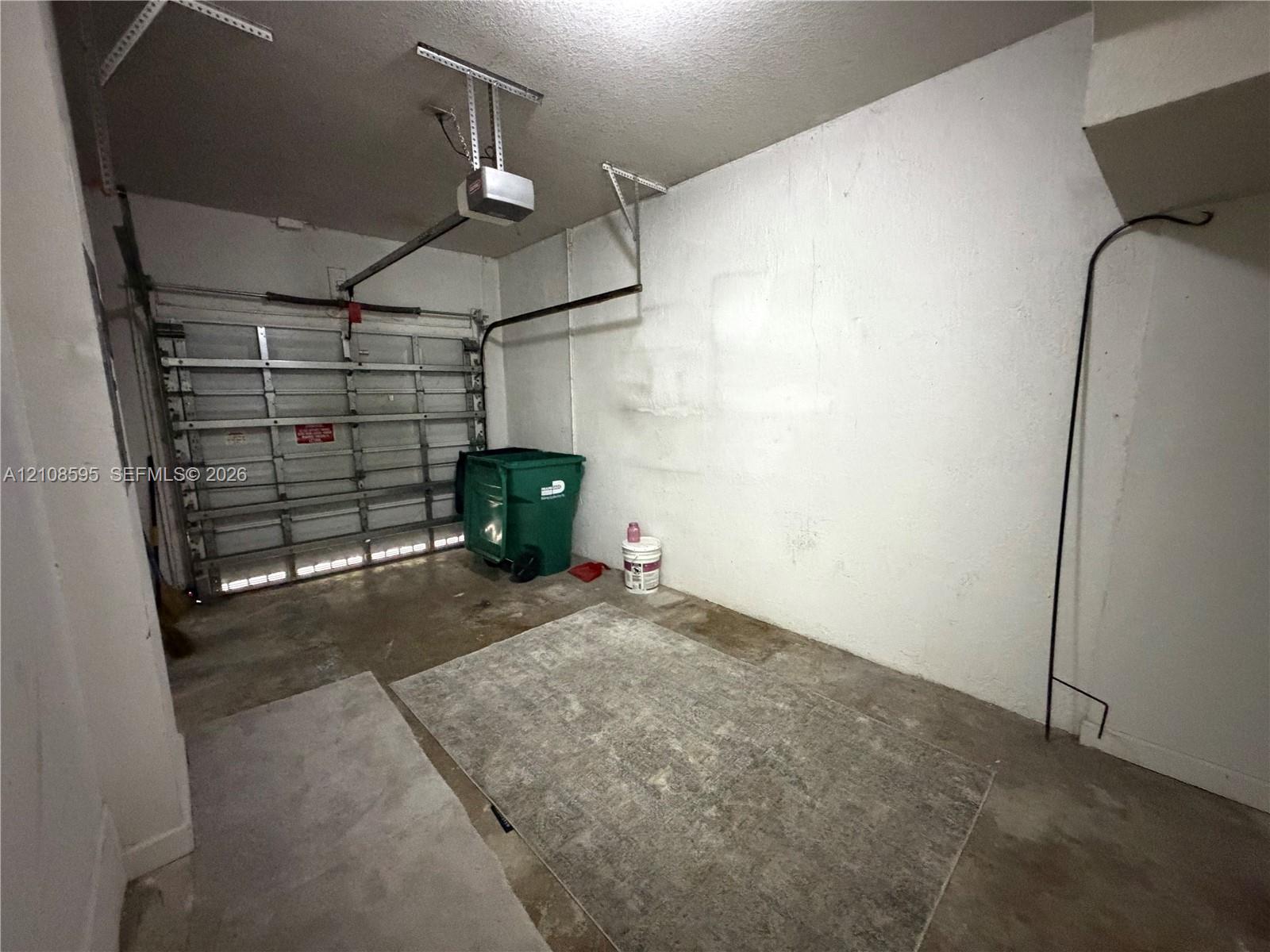 Enclosed garage space featuring a metal sectional door and automated overhead door opener