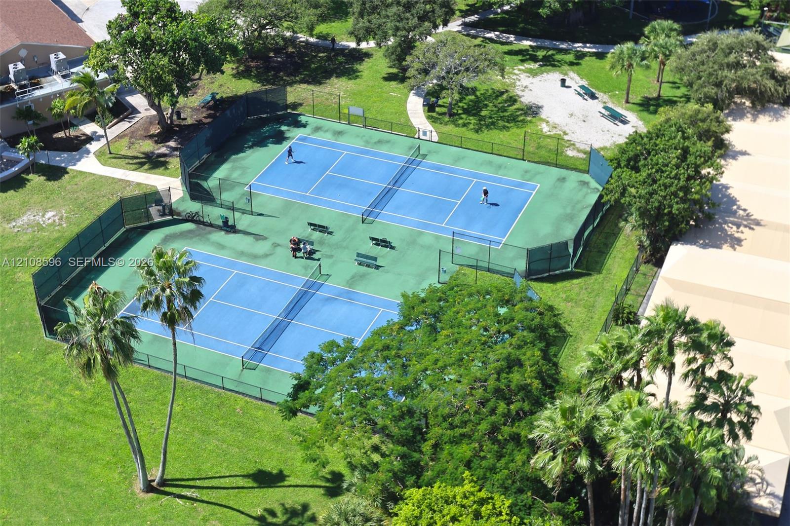 Dual tennis courts featuring hard-surface playing areas, perimeter chain-link fencing, and professional-grade netting Dual tennis courts featuring hard-surface playing areas, perimeter chain-link fencing, and professional-grade netting