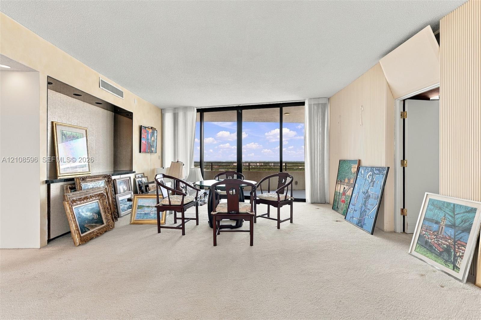 Living area featuring floor-to-ceiling glass sliding doors, a built-in recessed wall niche with integrated lighting, and carpeted flooring
