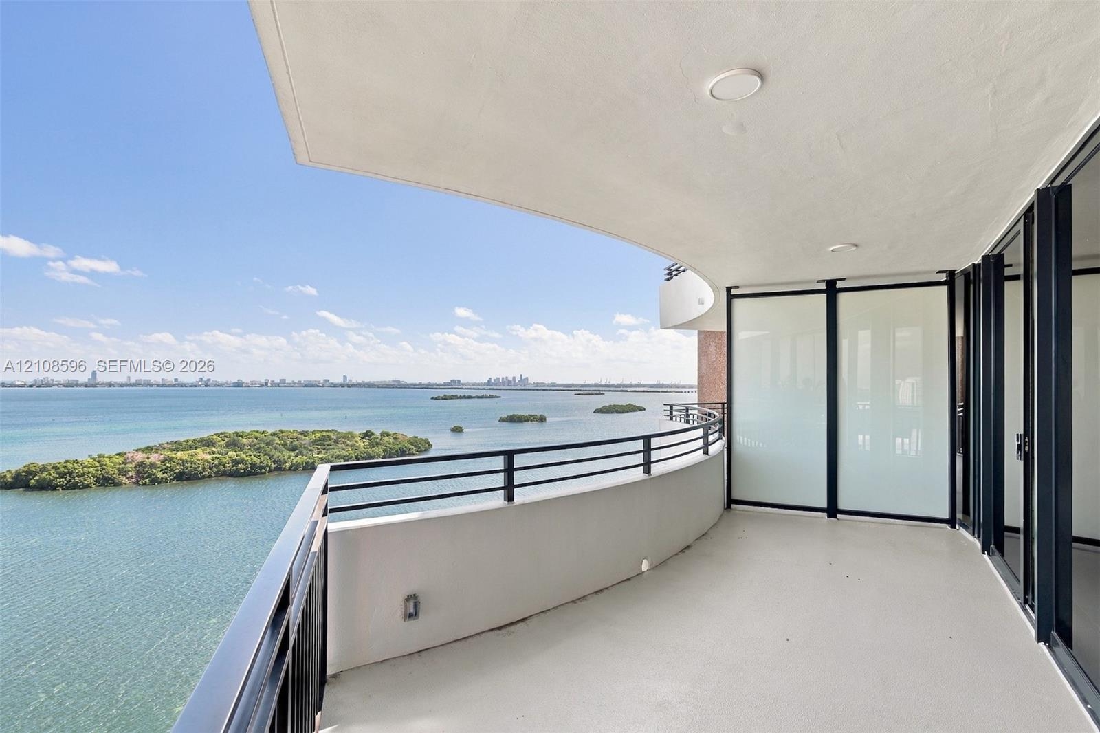 Curved balcony featuring a concrete surface, metal railing, frosted glass partition, and recessed ceiling lighting