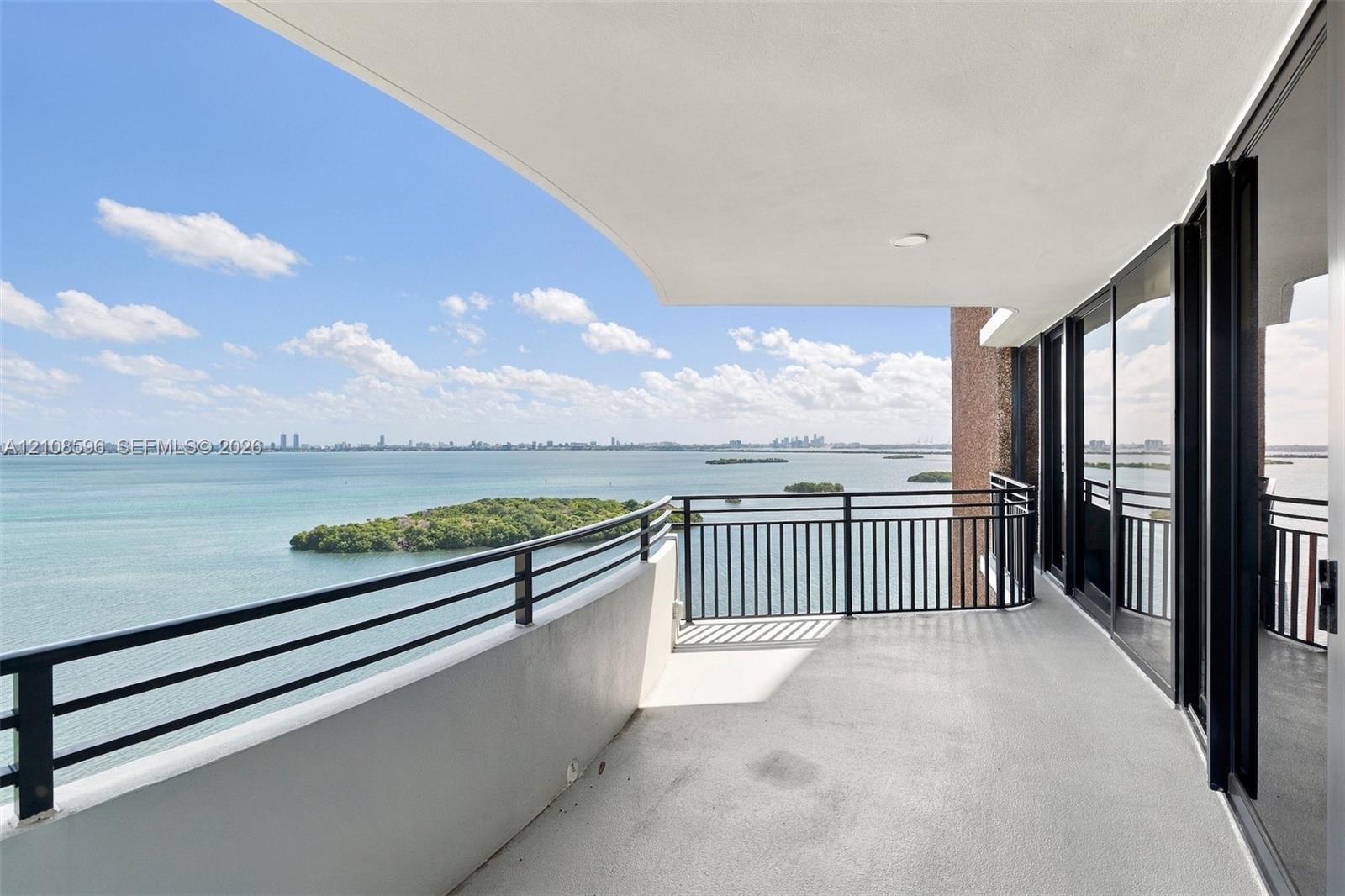 Covered balcony featuring a metal railing, concrete flooring, and sliding glass panel doors